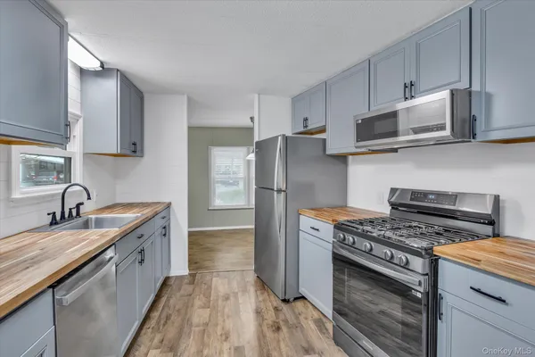 a kitchen with stainless steel appliances a sink a stove a microwave and wooden cabinets