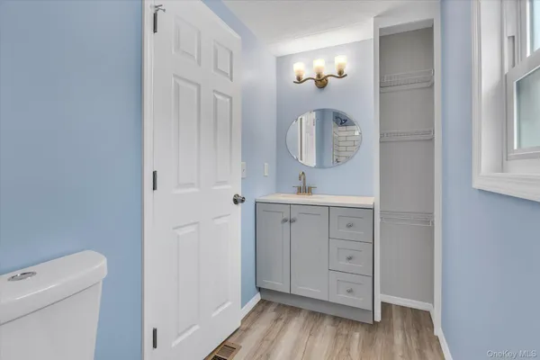 a bathroom with a sink a mirror and wooden floor
