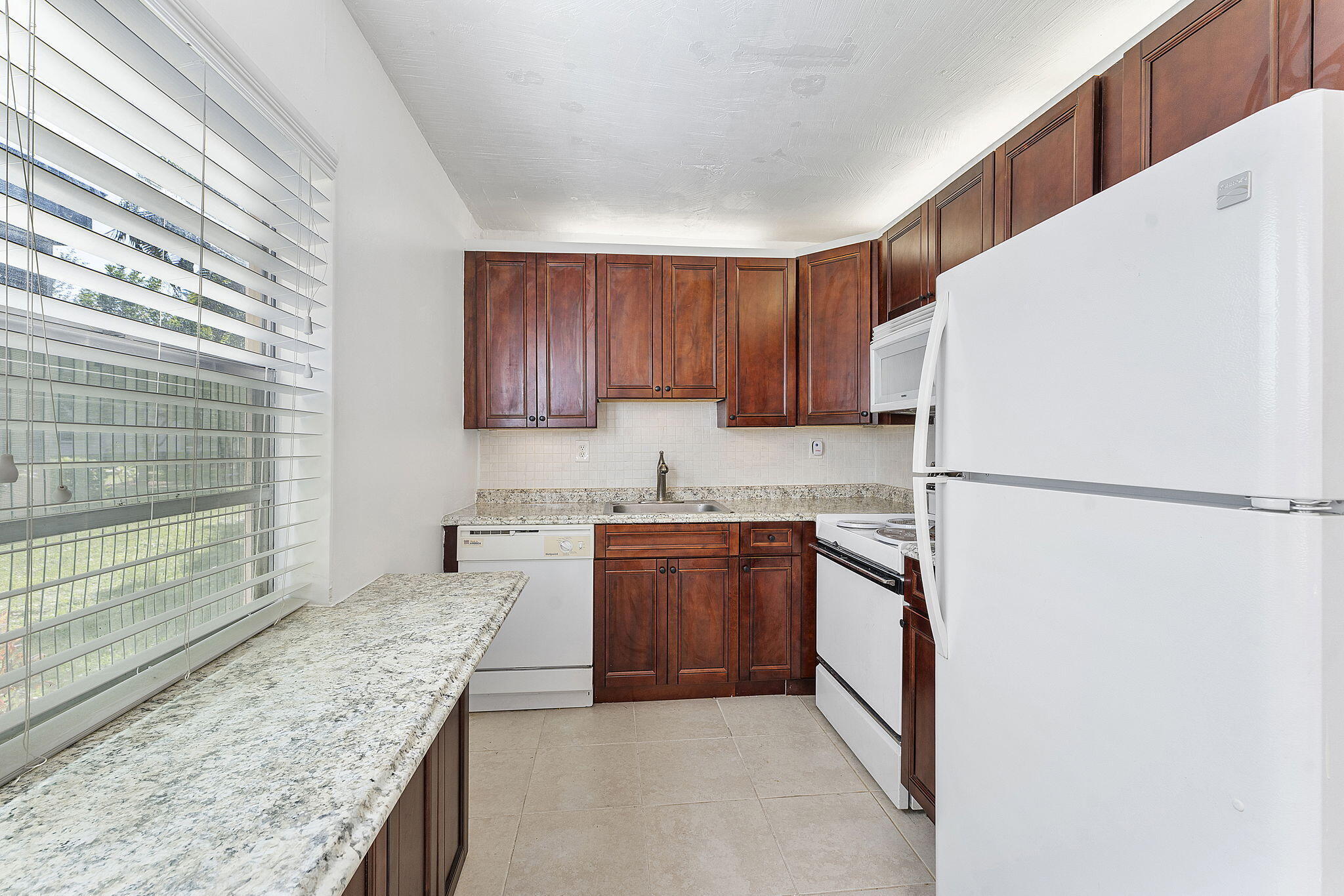 877 Flanders South Delray Beach, FL 33484 - Photo 14 of 27 a kitchen with stainless steel appliances granite countertop a refrigerator and a sink