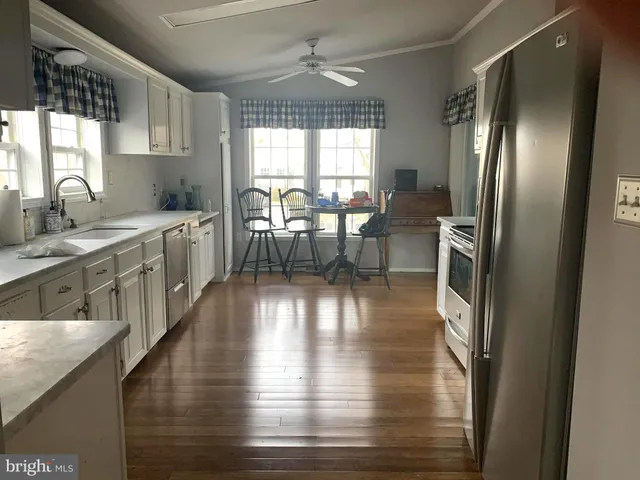 a kitchen with stainless steel appliances granite countertop a stove refrigerator and a dining table with wooden floor