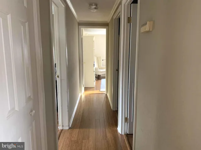 a view of a hallway with wooden floor and a bathroom