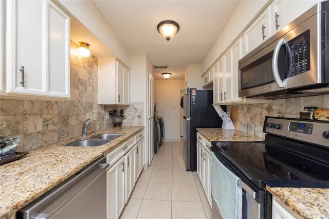 a kitchen with stainless steel appliances granite countertop a sink a stove and a wooden cabinets