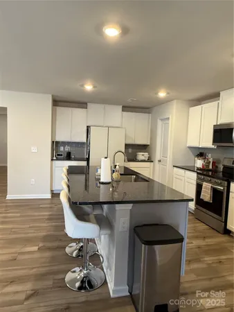 a kitchen with kitchen island granite countertop a sink and a refrigerator