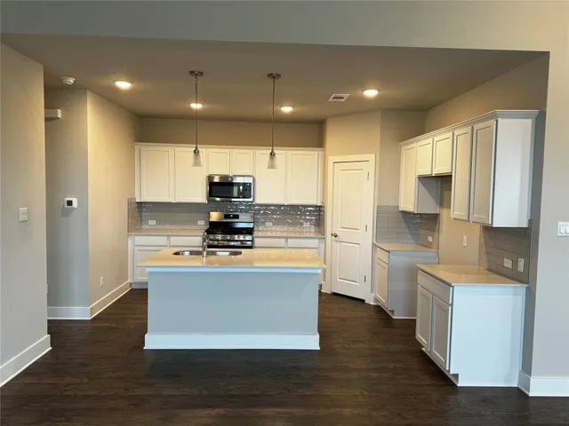 a large kitchen with stainless steel appliances granite countertop a stove a sink and a refrigerator