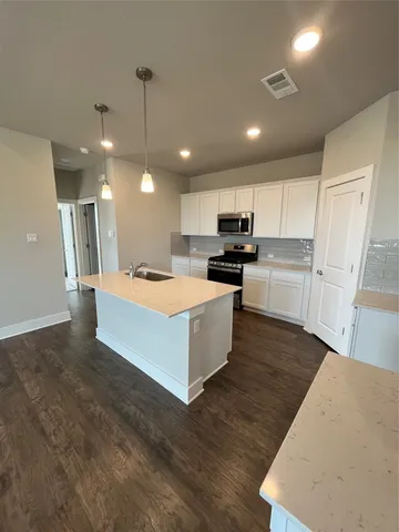 a large kitchen with kitchen island a stove a sink a refrigerator and cabinets