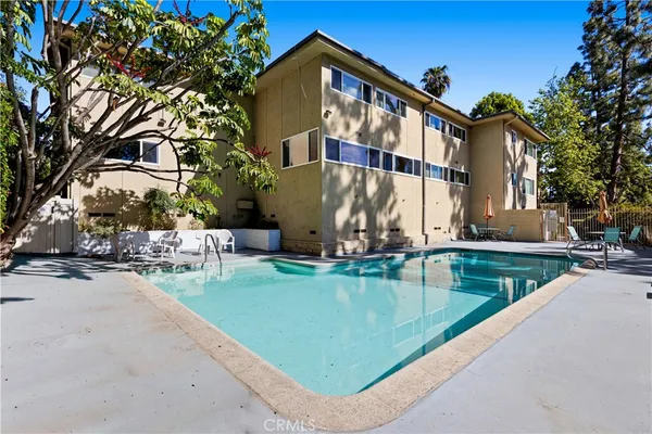 a view of swimming pool with outdoor seating and house in the background