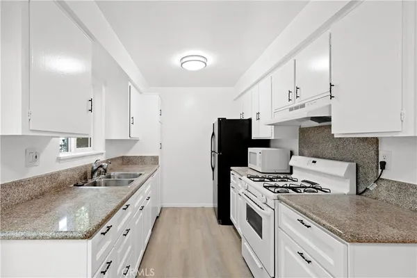 a kitchen with granite countertop a sink stove and refrigerator