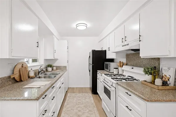 a kitchen with granite countertop a sink a stove and refrigerator