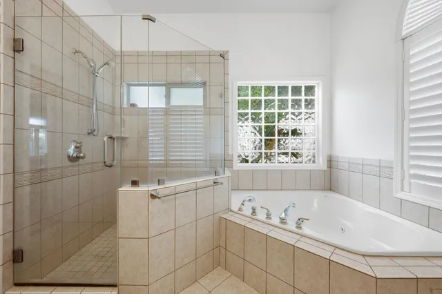 a bathroom with a tub a sink a window and a shower