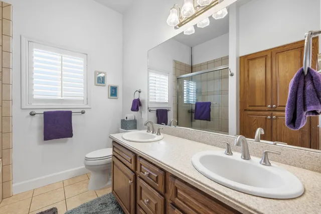 a bathroom with double vanity sinks a large mirror and a shower