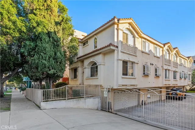 a big white house with a white roof and table and chairs next to a yard