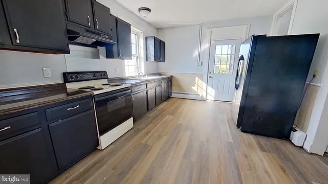 a kitchen with stainless steel appliances a refrigerator and wooden floor