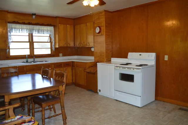 a kitchen with stainless steel appliances granite countertop a refrigerator a stove and a sink with wooden cabinets