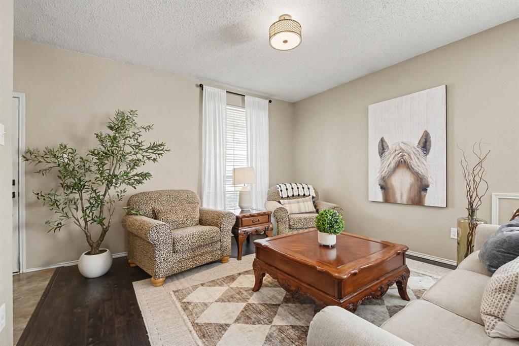 Living area featuring wood-finish flooring, neutral wall tones, and a window with blinds
