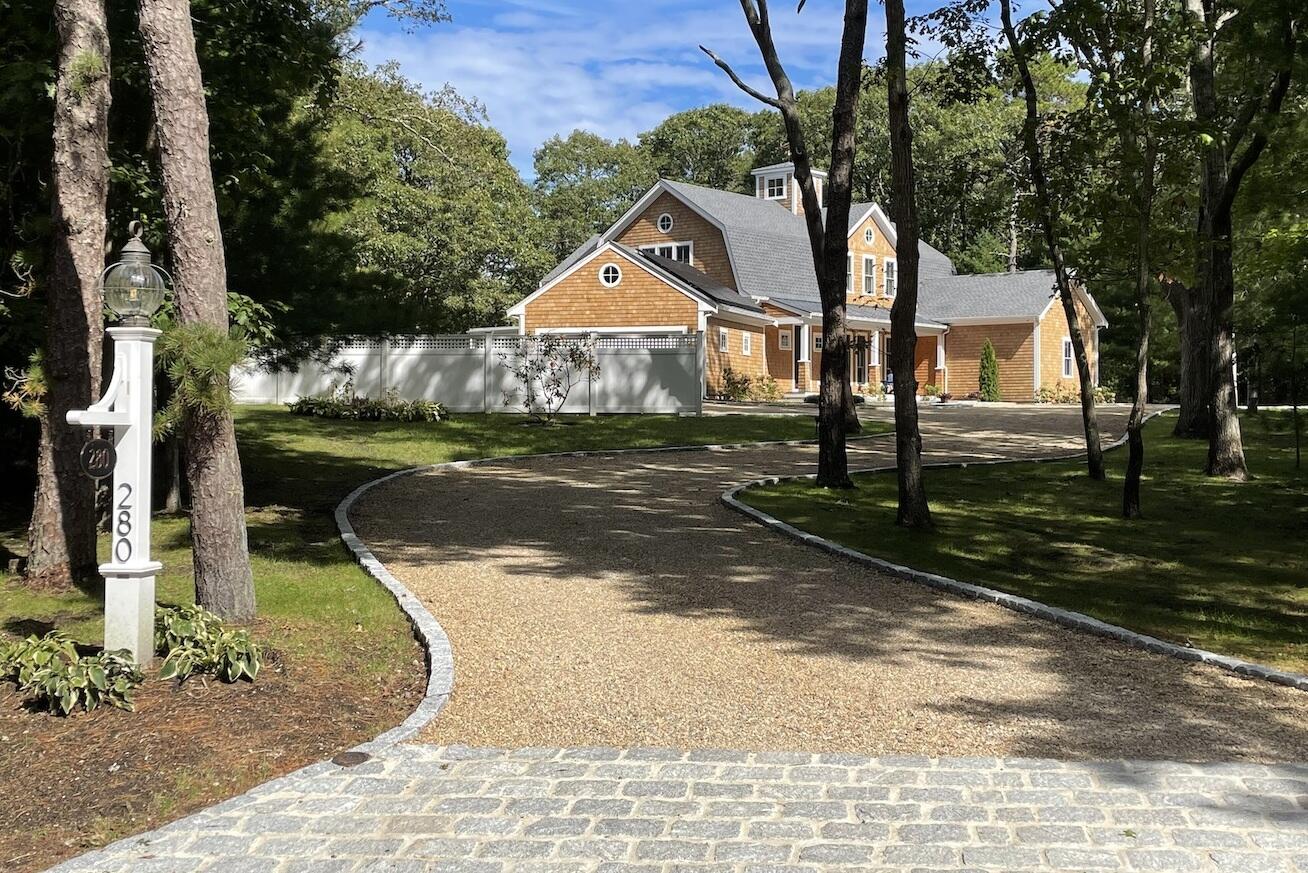 a street view with large trees and wooden fence