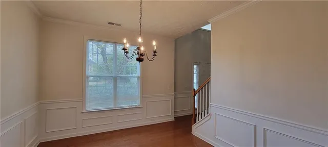 an empty room with chandelier fan and windows