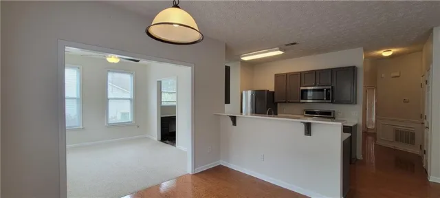 a kitchen with kitchen island granite countertop stainless steel appliances cabinets a sink and a refrigerator