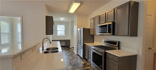 a kitchen with stainless steel appliances a stove microwave and sink