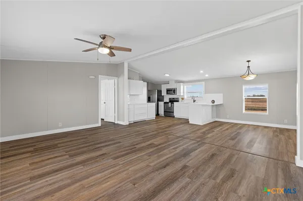 a view of empty room with wooden floor and ceiling fan