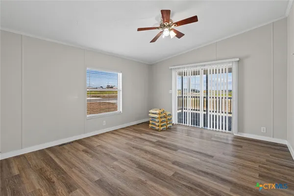 a view of an empty room with a window and wooden floor