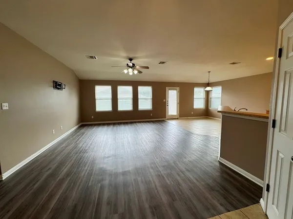 a view of an empty room with a window and wooden floor