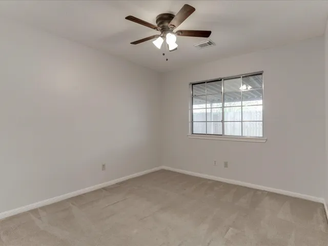 an empty room with a chandelier fan and windows