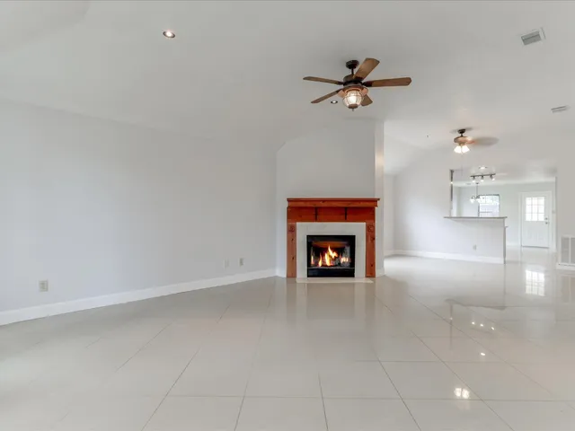an empty room with a ceiling fan and a fireplace