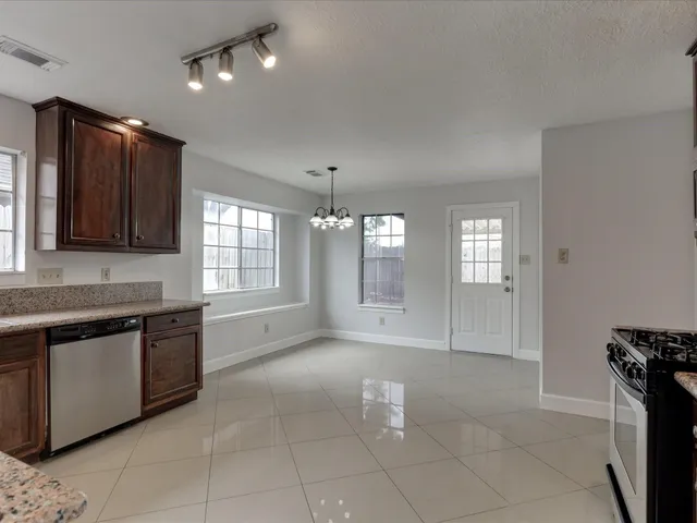 a large kitchen with granite countertop a stove a sink dishwasher and a microwave oven on the granite countertops