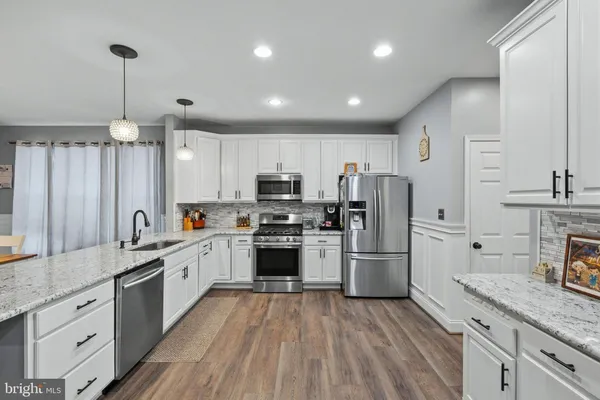 a large kitchen with granite countertop a large counter top appliances and cabinets