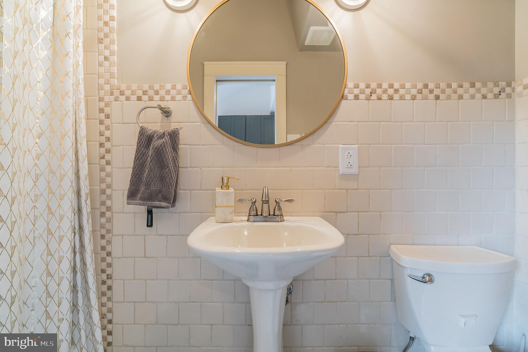 229 Benezet Street Philadelphia, PA 19118 - Photo 22 of 36 a bathroom with a sink a toilet and a mirror