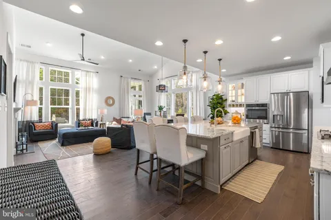 a kitchen with stainless steel appliances kitchen island granite countertop a refrigerator a stove a sink dishwasher and a dining table with wooden floor