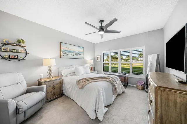 a bed room with a bed a couch and a flat tv screen on dresser