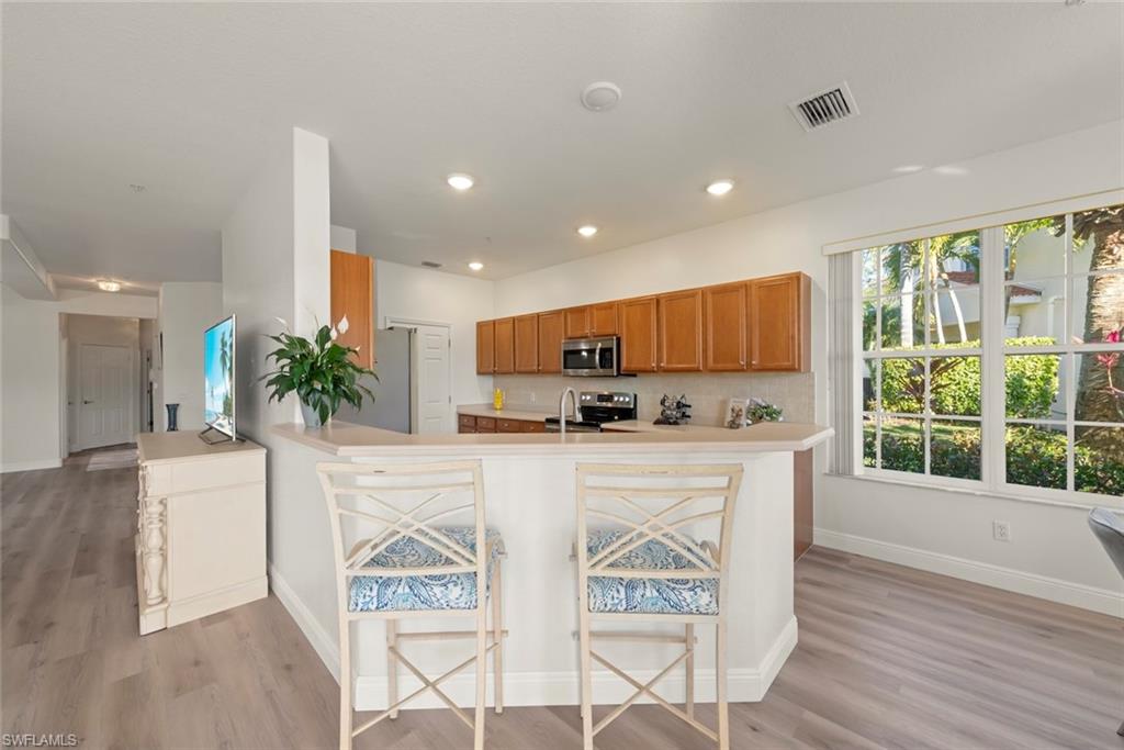 4630 Winged Foot Court, Unit 101 Naples, FL 34112 - Photo 15 of 43 a kitchen with stainless steel appliances kitchen island granite countertop a stove a sink a microwave and a refrigerator
