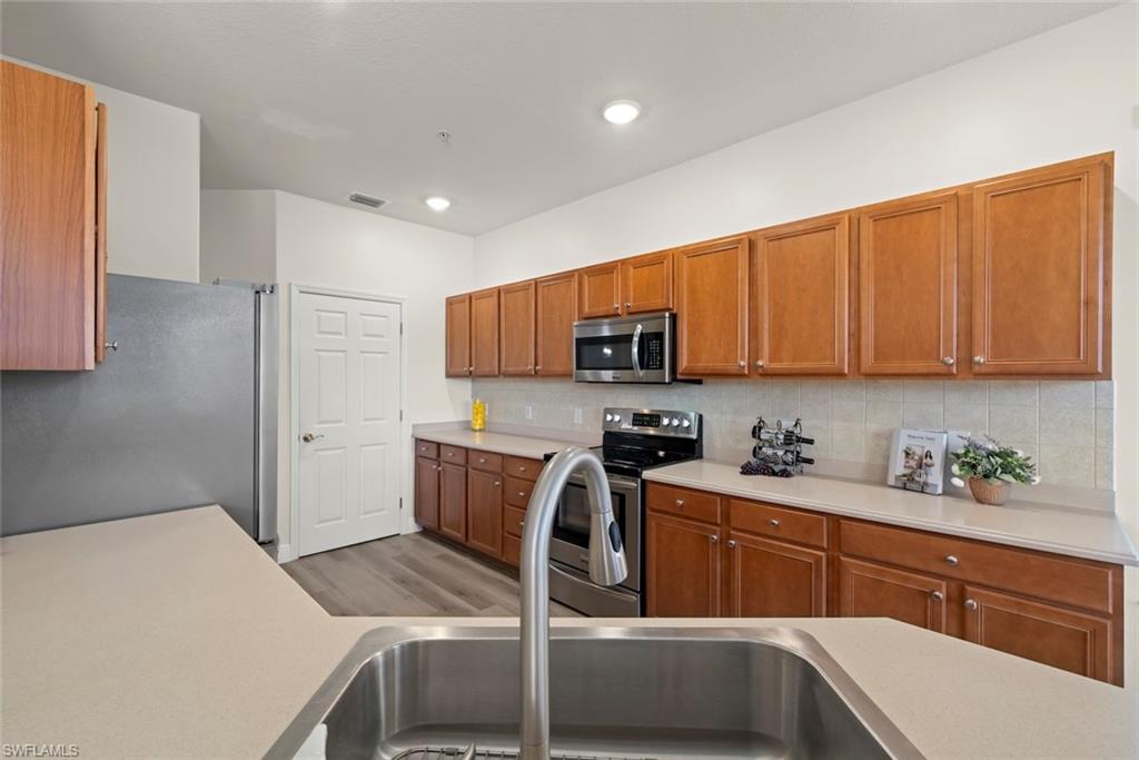 4630 Winged Foot Court, Unit 101 Naples, FL 34112 - Photo 17 of 43 a kitchen with stainless steel appliances granite countertop a sink refrigerator and cabinets