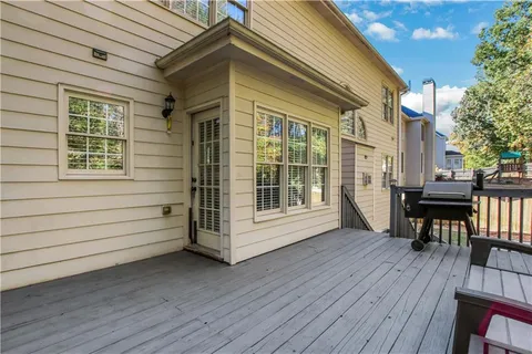 a view of a deck with table and chairs with wooden floor and fence and a barbeque