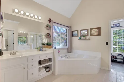 a bathroom with a tub a double vanity sink a window and a mirror