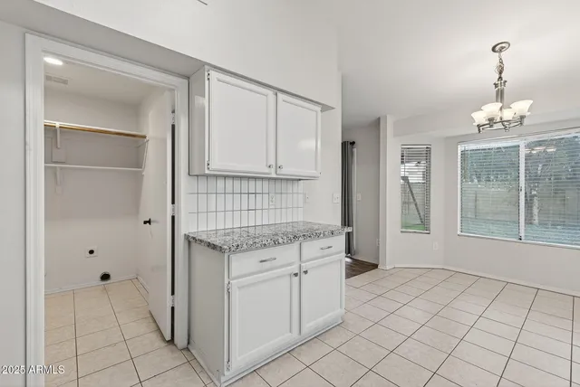 a kitchen with white cabinets and window