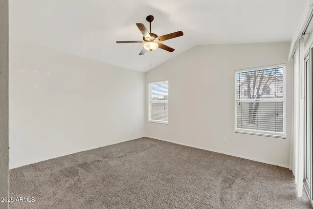 an empty room with window and ceiling fan