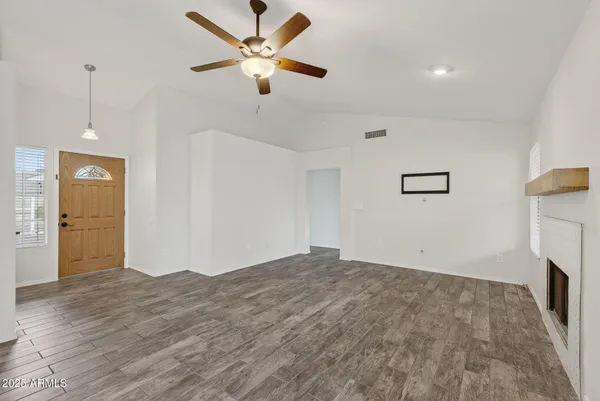 a view of empty room with wooden floor and ceiling fan