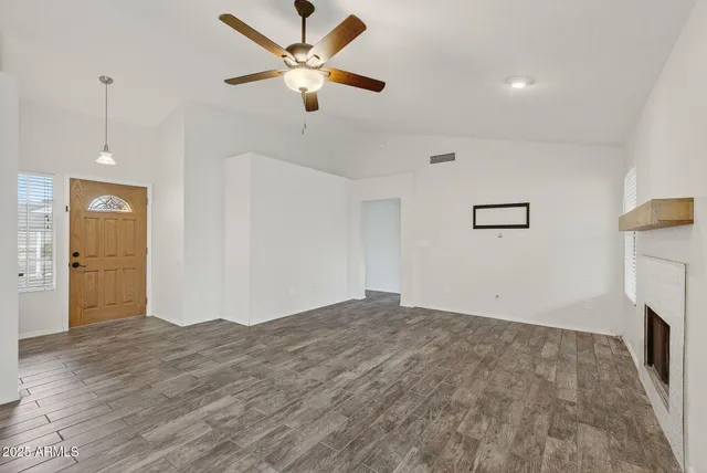 a view of empty room with wooden floor and ceiling fan