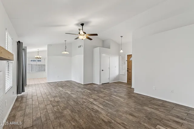 a view of a big room with wooden floor and a chandelier fan