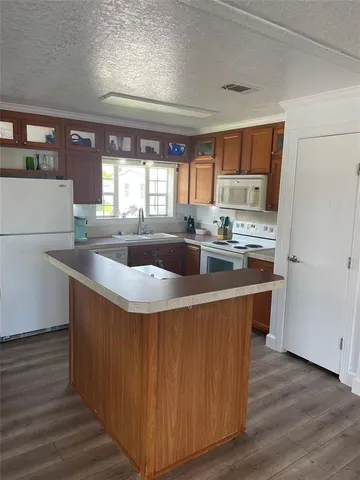 a kitchen with stainless steel appliances a sink a stove a refrigerator and island with wooden floor