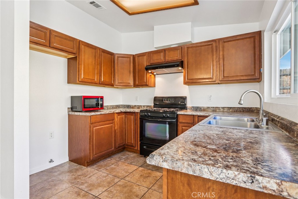 12059 Elk Boulevard Riverside, CA 92505 - Photo 10 of 29 a kitchen with stainless steel appliances granite countertop a sink stove and refrigerator