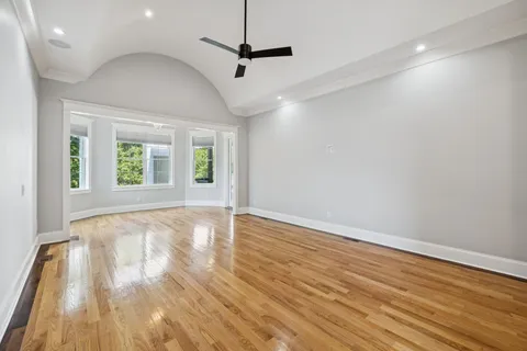 a view of empty room with wooden floor and ceiling fan
