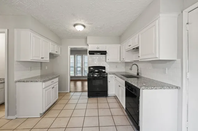a kitchen with stainless steel appliances granite countertop a sink stove oven and white cabinets