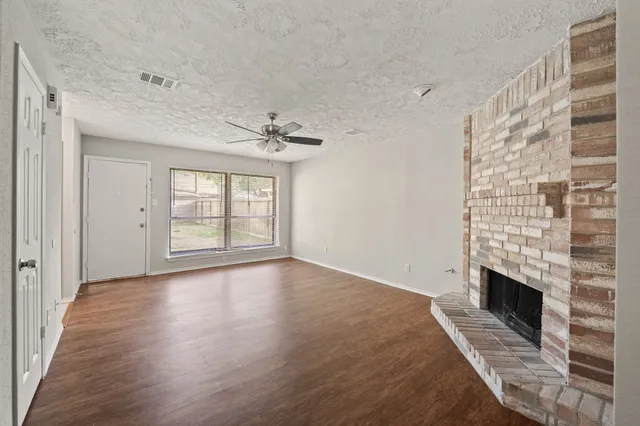 a view of an empty room with a fireplace and a window