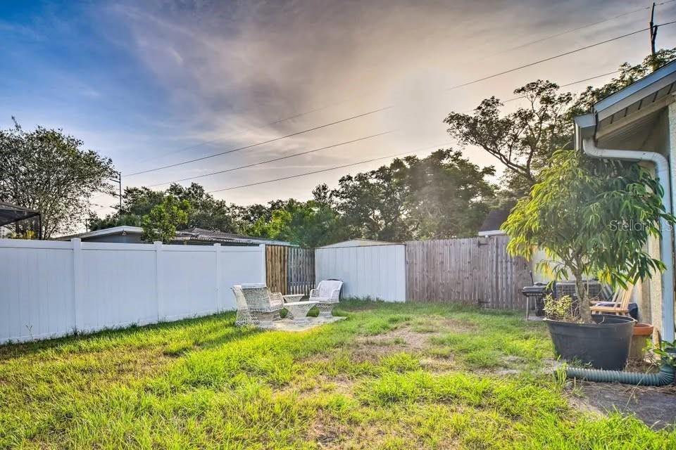 2196 Bell Cheer Drive Clearwater, FL 33764 - Photo 41 of 55 a backyard of a house with table and chairs plants and large tree