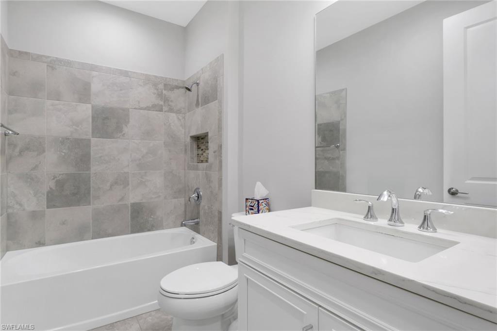 2231 Marquesa Circle Naples, FL 34112 - Photo 21 of 38 a bathroom with a granite countertop bathtub shower sink vanity mirror and toilet