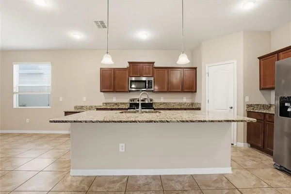 a kitchen with stainless steel appliances granite countertop a sink a stove top oven a counter space and cabinets