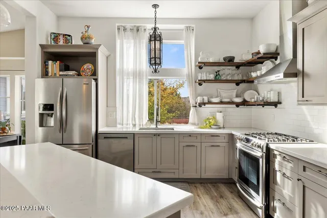 a kitchen with stainless steel appliances granite countertop a refrigerator a stove and a sink with wooden floor